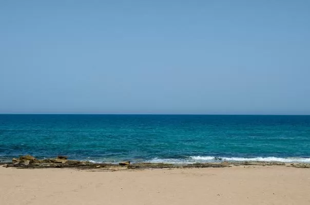 חוף חולי עם סלעים פוגש את האוקיינוס הכחול הצלול תחת שמים בהירים - תמר על הים, צימר בצפון, נהריה, גליל מערבי