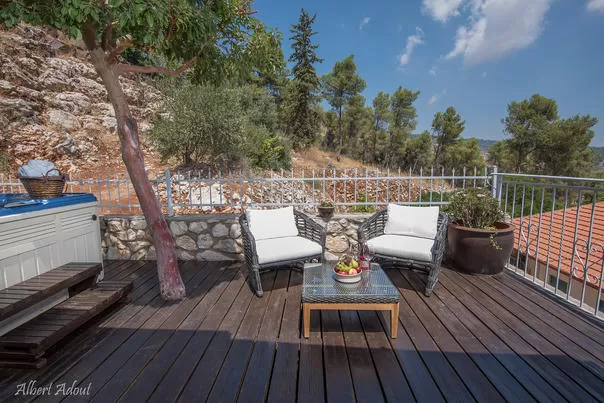 מרפסת חיצונית עם כיסאות נצרים, צמחים בעציצים ונוף הררי של ראש פינה - פינה בהר- ראש פינה, אתר נופש בצפון, ראש פינה, גליל עליון