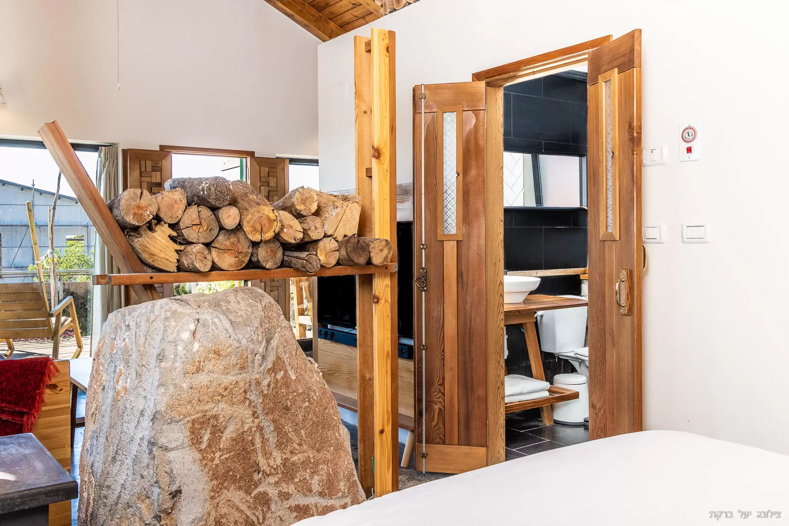 A huge basalt rock and a pile of firewood on top of it in the center of the cabin - Hazimmer Hayarok Vehadom, Maale Gamla, The Golan Heights and the Hermon