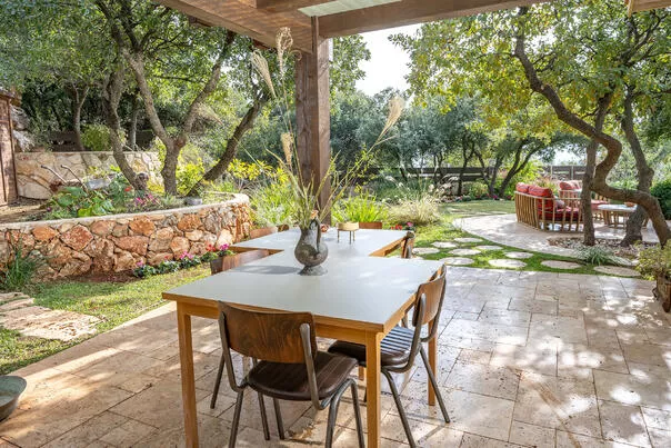 שולחן וחצר עץ עם כיסאות, וזרי פרחים, מוקפים בעצים וחומת אבן - אזמרה אמירים, סוויטה בצפון, אמירים, גליל עליון